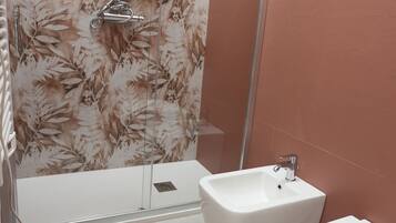 Ein Badezimmer mit Dusche, Bidet und Toilette.