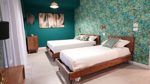 A room with two wooden beds, a wooden nightstand, a TV, and a wall with a leafy pattern. - Ross Family Suites  (Reggio Calabria)