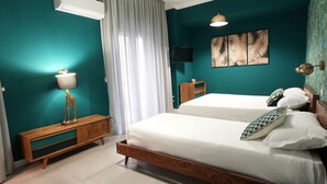 A bedroom with teal walls, a wooden bed frame, white bedding, a wooden nightstand, a wall-mounted TV, and a ceiling light. - Ross Family Suites  (Reggio Calabria)