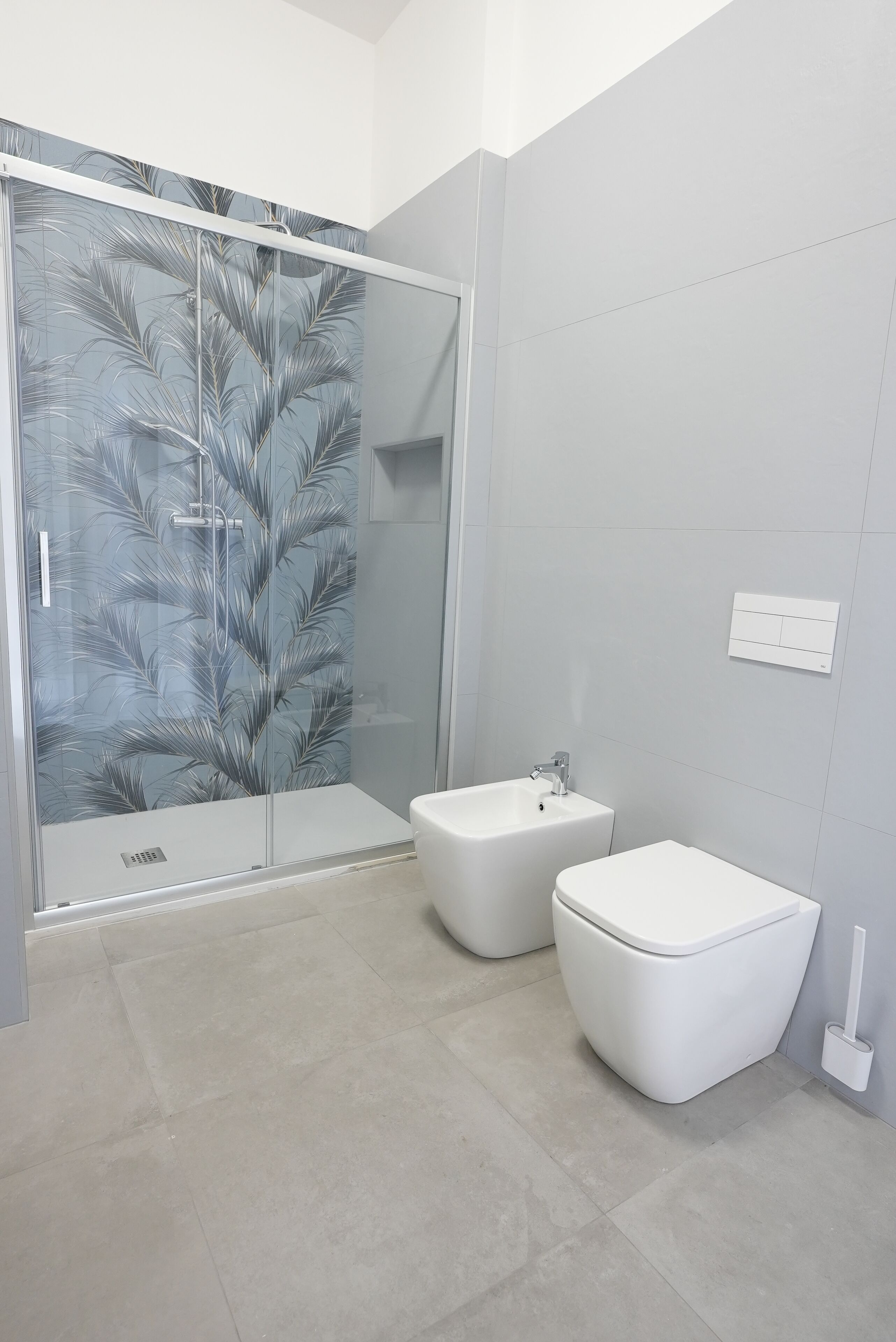 Un baño moderno con cabina de ducha de vidrio, lavabo pedestal y inodoro.