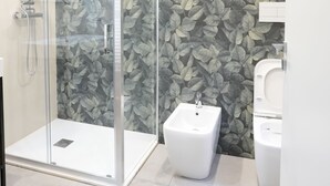A modern bathroom with a glass-enclosed shower, a bidet, and a toilet. - Ross Family Suites  (Reggio Calabria)