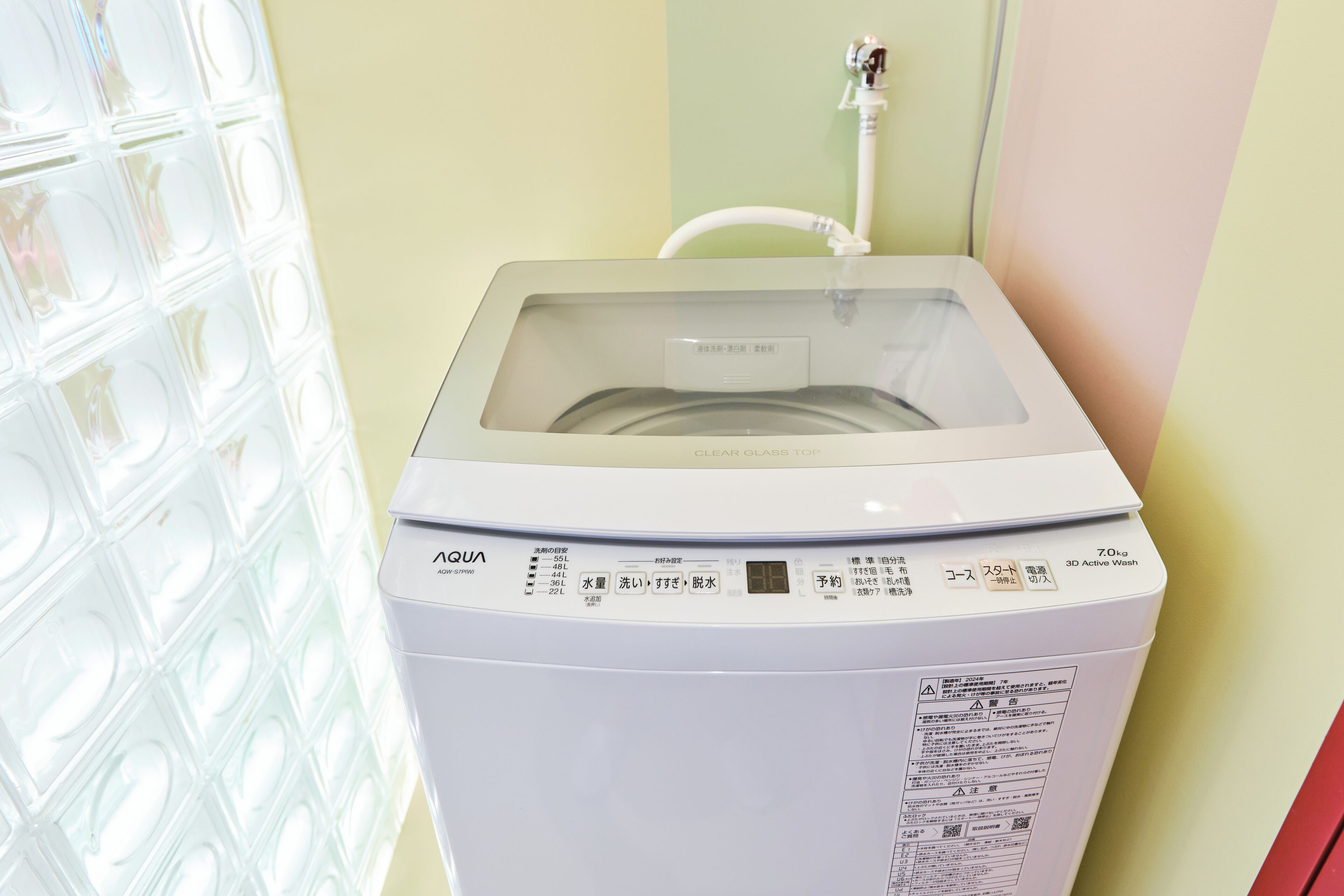 A white washing machine with a clear glass top, control panel, and a label indicating it is a 7.0kg model.