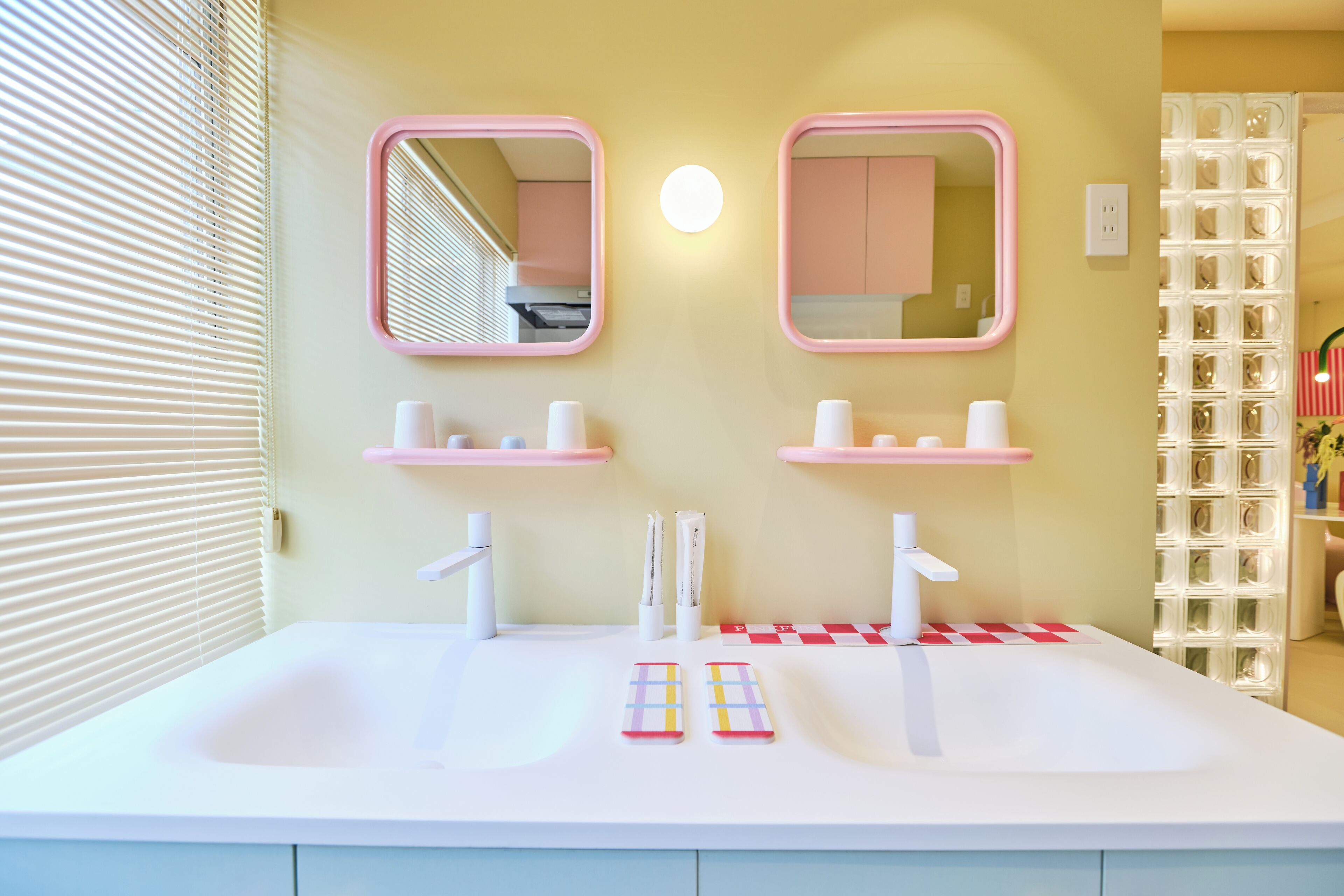 Een badkamer met twee wastafels, roze spiegels en een wit aanrecht.