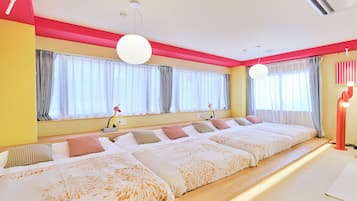 Een hotelkamer met een groot bed, meerdere kussens, een nachtkastje en een raam met gordijnen.