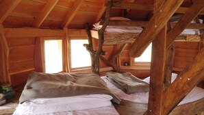 A rustic cabin with wooden beams, a loft bed, and a window providing natural light. - Cabane perchée Arbràmâne (5 people) (Vittel)