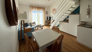 Eine moderne Küche mit Essbereich, einer Treppe und einem Wohnzimmer mit Sofa und Fernseher.