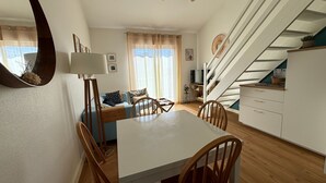 Eine moderne Küche mit Essbereich, einer Treppe und einem Wohnzimmer mit Sofa und Fernseher.