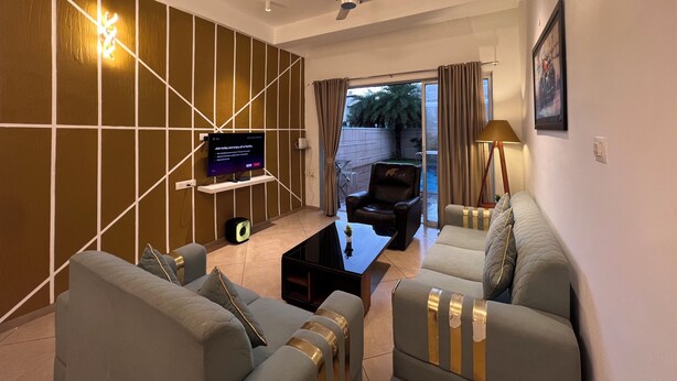 Een moderne woonkamer met een flatscreen televisie, een plafondventilator en een zithoek.