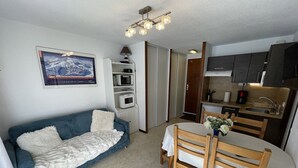 A compact living space with a sofa, dining table, and kitchenette. - Functional apartment near slopes, ideal for 4-6 people (Le Lioran)