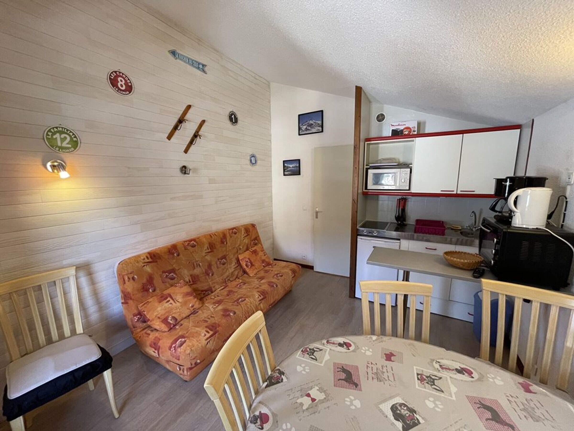 En kompakt opholdsstue med sofa, spisebord og tekøkken.