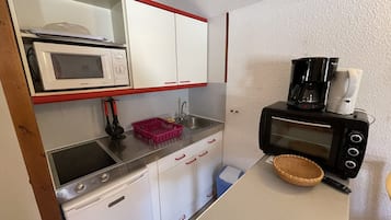 A compact kitchenette with a microwave, toaster, coffee maker, and a small sink.
