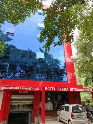 A hotel with a red facade, a restaurant and banquet hall, and a parking area. - Hotel Rekha International (Rajgir)
