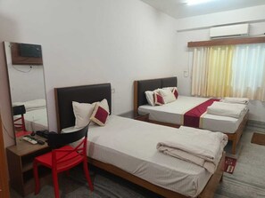 A hotel room with three beds, a desk, a chair, and a mirror. - Hotel Rekha International (Rajgir)