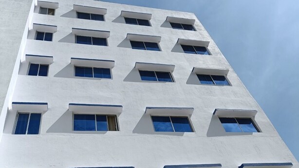 A white building with multiple windows and balconies. - Hotel Rekha International (Rajgir)