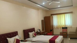 A hotel room with three beds, a desk, a chair, and a wardrobe. - Hotel Rekha International (Rajgir)