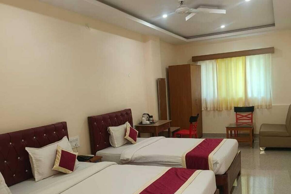A hotel room with three beds, a desk, a chair, and a wardrobe.