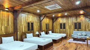 A room with four beds arranged in a row, wooden walls, and a sofa with cushions.