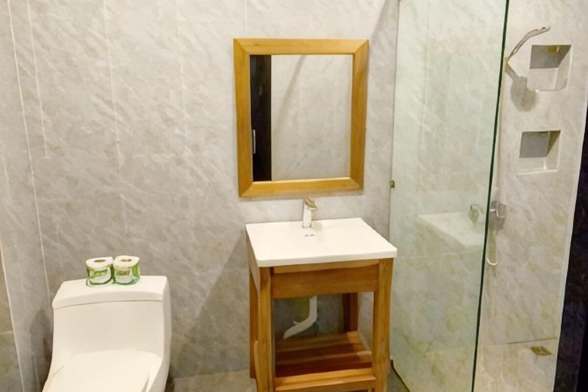Une salle de bain comprenant des toilettes, un lavabo, un miroir et un espace douche.