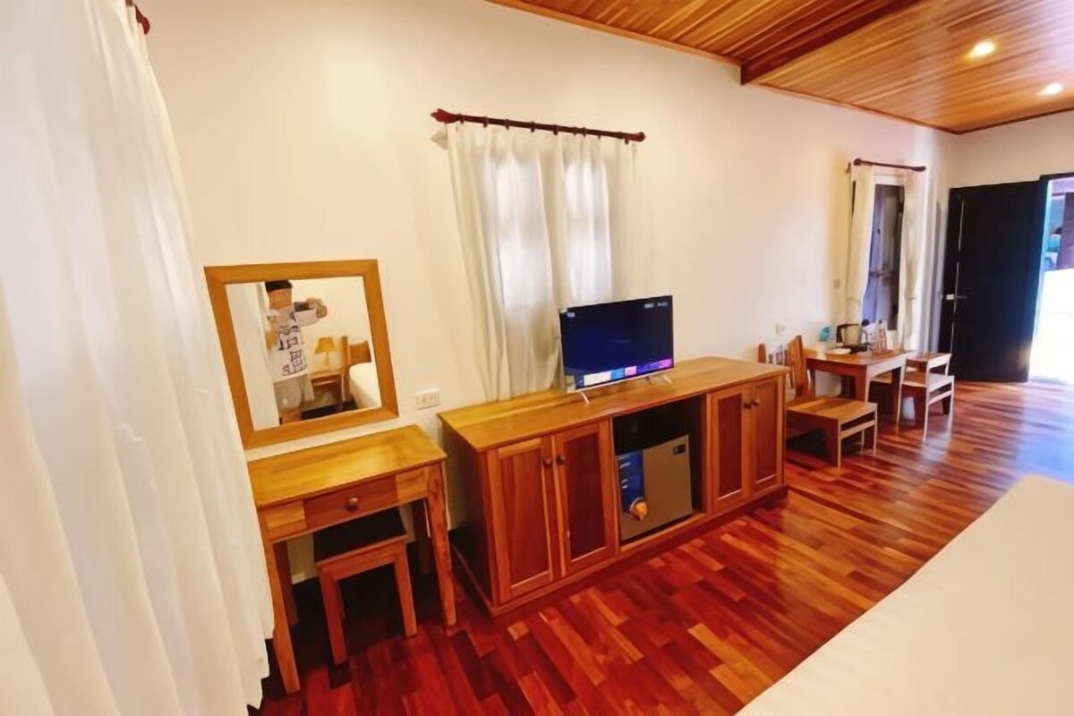 Une pièce comprenant un meuble en bois, un téléviseur et un coin repas avec une table et des chaises.