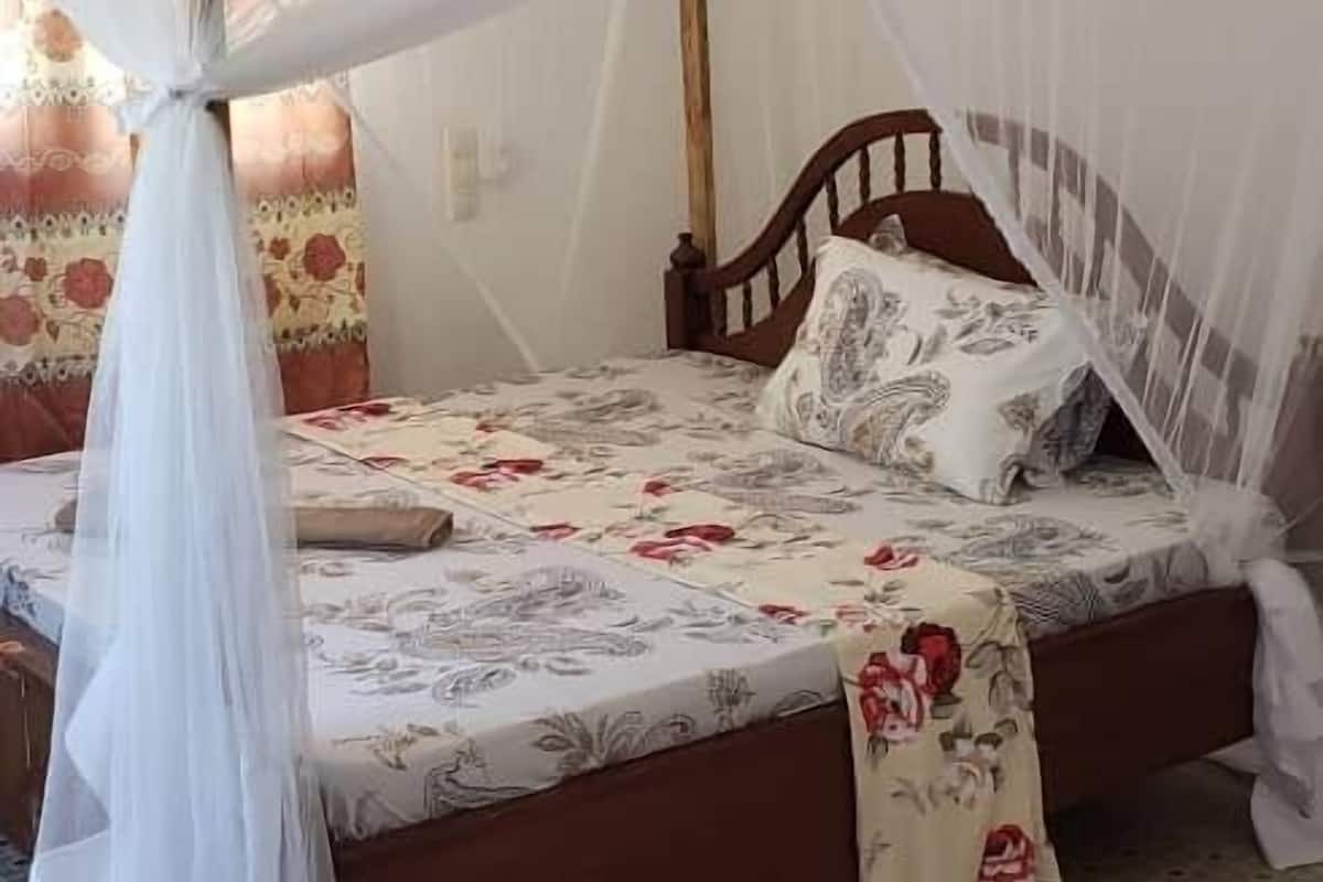 Un lit simple avec un baldaquin, une couvre-lit à motifs et un coussin à fleurs.