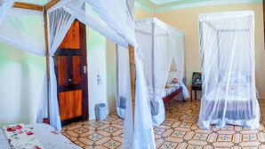 A room with a bed covered by a canopy, another bed with a similar canopy, a wooden door, a small table with a painting, and patterned floor tiles. - Saba house 24 (Paje)