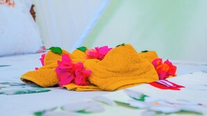 A bed with a floral-patterned bedspread and a yellow towel with pink flowers. - Saba house 24 (Paje)