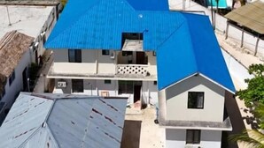 A coastal residential area with houses featuring blue roofs, a clear view of the ocean, and palm trees. - Saba house 24 (Paje)