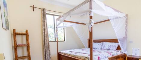 A four-poster bed with a canopy, a wooden ladder, a window with curtains, and a ceiling fan.