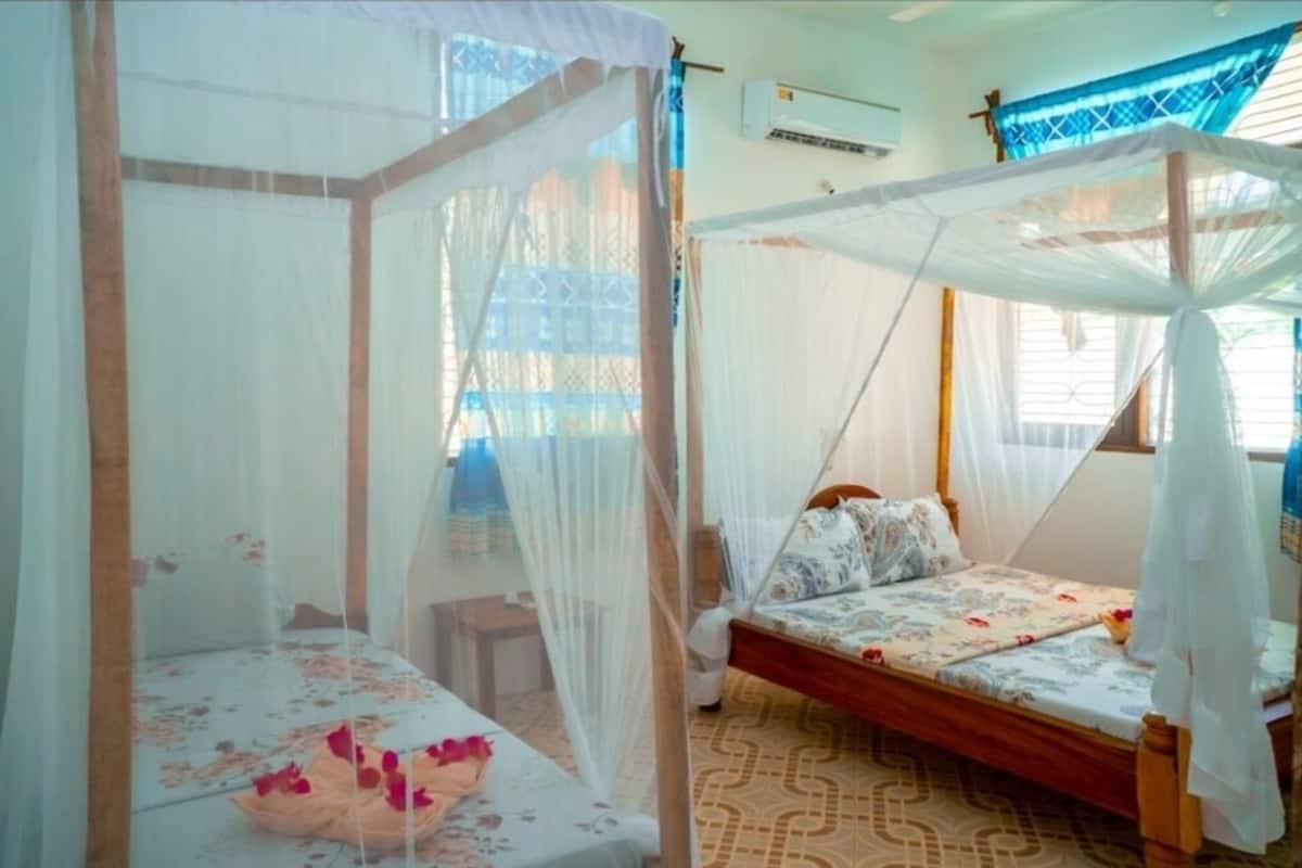 Une chambre avec deux lits, chacun surmonté d’un baldaquin et doté d’une moustiquaire.