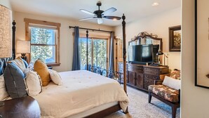 A bedroom with a four-poster bed, a ceiling fan, a television, and a large window with a view of trees. - 87 Maggie. Walkability! Shuttle. Pet friendly. (Breckenridge)