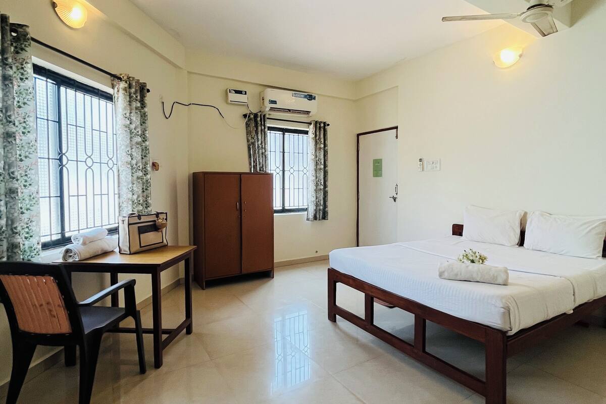 Una habitación de hotel con cama, escritorio, armario y ventilador de techo.