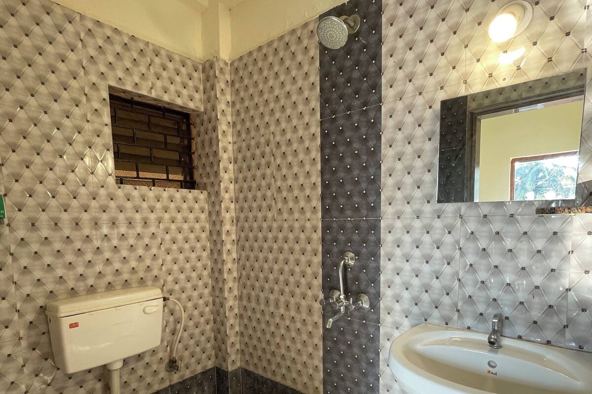 Un baño con inodoro, bidé y lavabo, con un papel tapiz estampado y baldosas tipo espiga.
