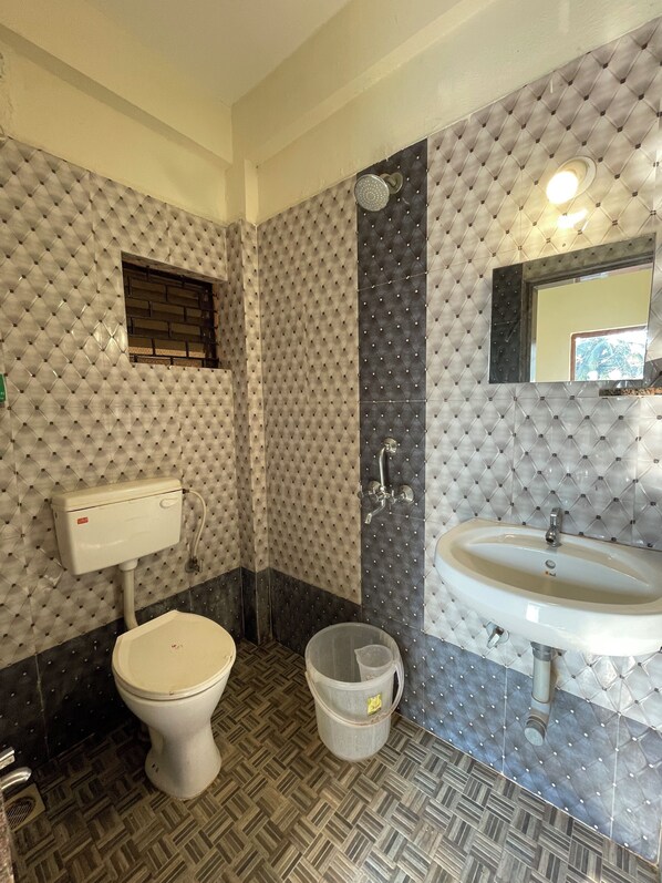 A bathroom with a toilet, bidet, and sink, featuring a patterned wall and herringbone floor tiles. - Jolene's Mandrem (Mandrem)