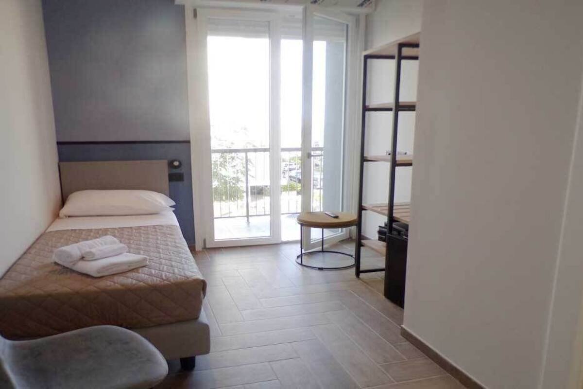 A bedroom with a bed, a chair, a small table, and a wardrobe.