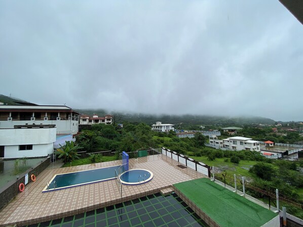 Une piscine sur le toit offrant une vue sur les bâtiments environnants et la végétation.