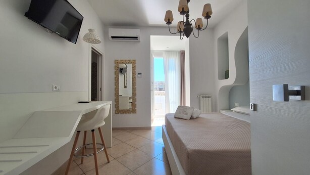 Une chambre à coucher comprenant un lit, un bureau, une chaise, un téléviseur et une salle de bain.