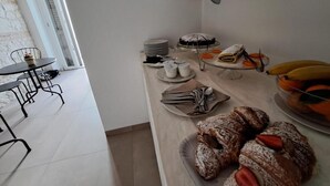 Un buffet de petit-déjeuner comprenant des viennoiseries, des fruits et un gâteau.