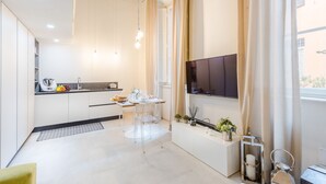 A modern kitchen with a dining area, a flat-screen TV, and a window with curtains. - Cortile Moderno Apartment (Lucca)