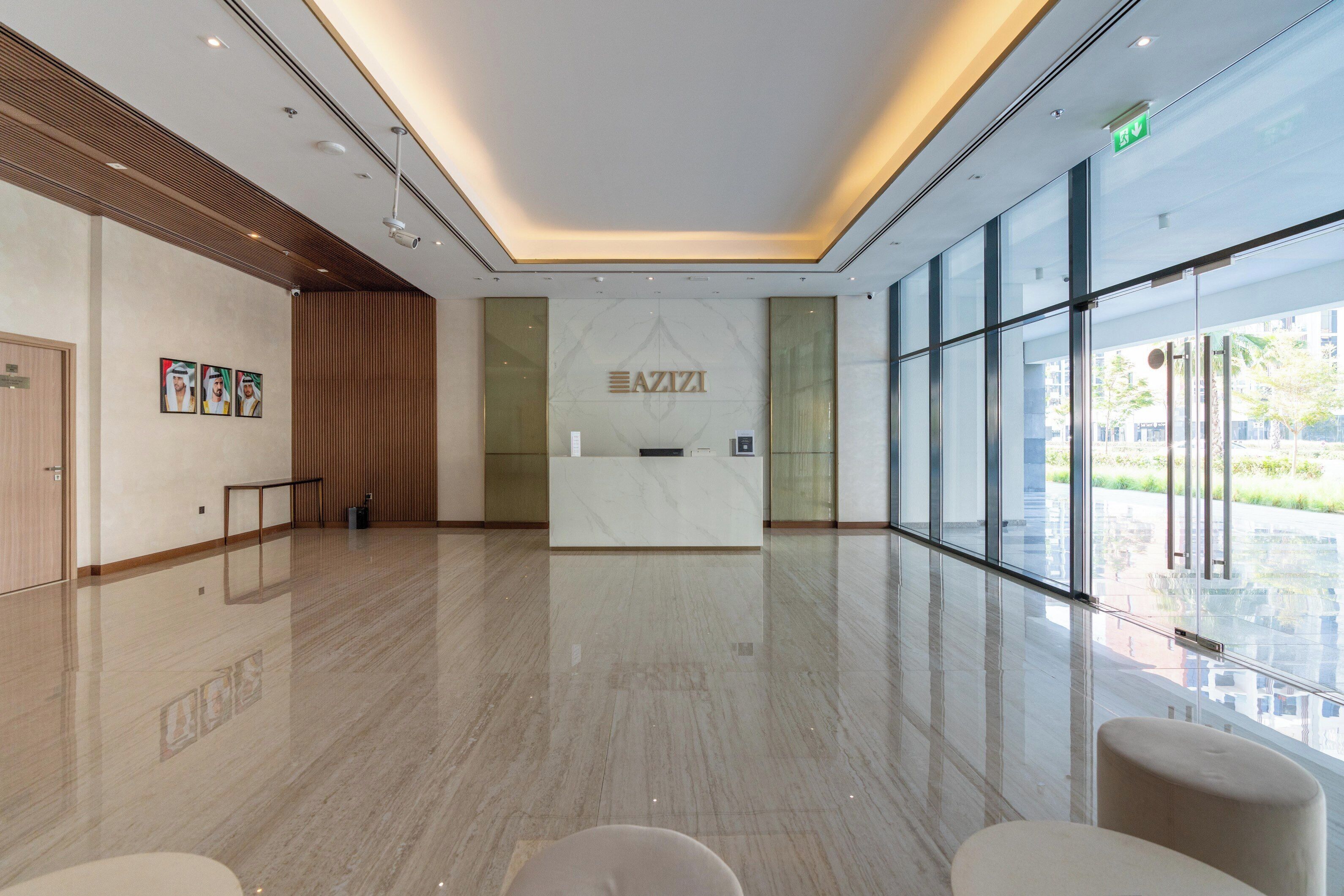 Un lobby moderno con una recepción, un panel de madera y ventanas amplias que ofrecen vistas al exterior.