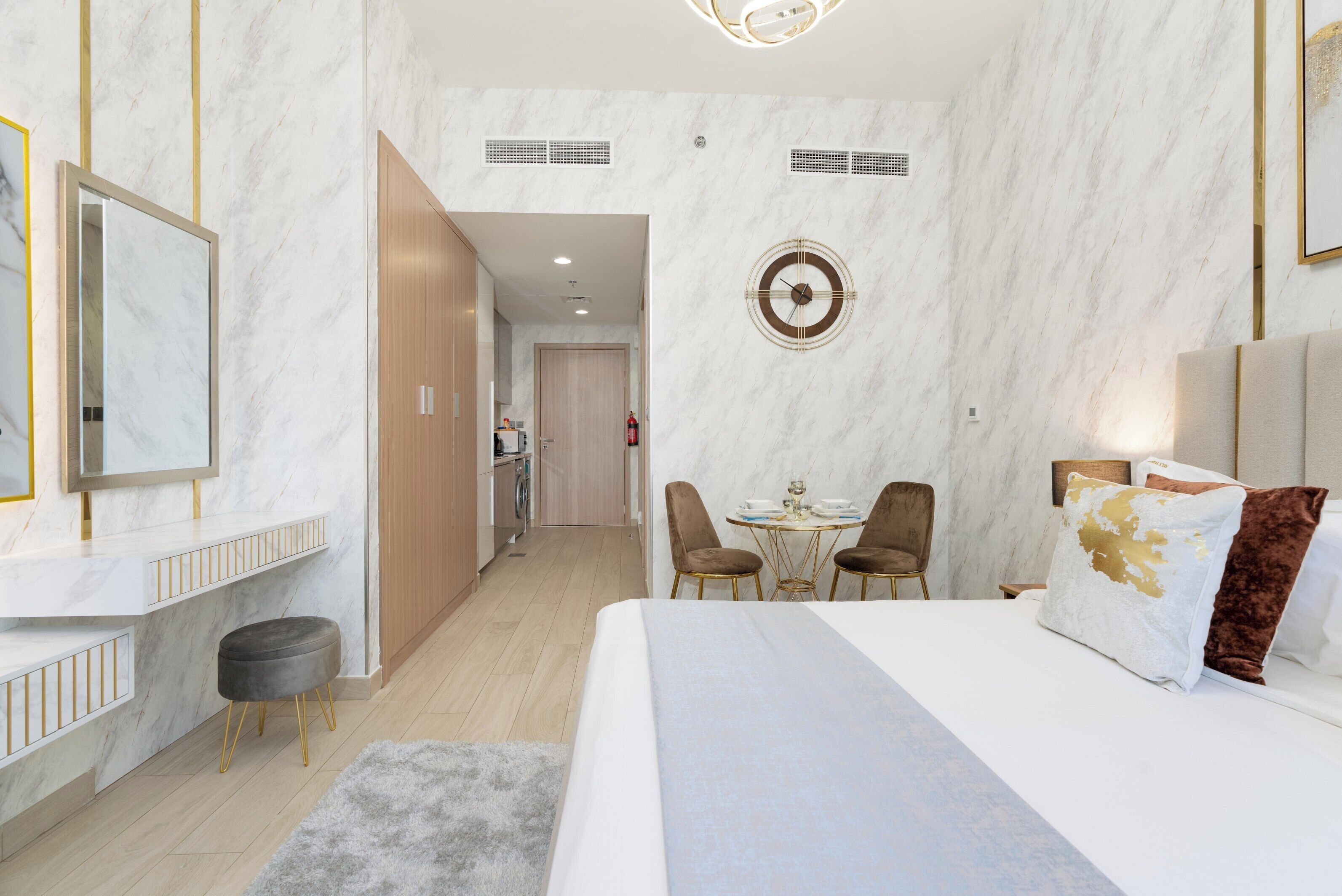 Une chambre d’hôtel moderne dotée d’un grand lit, d’un coin repas et d’une salle de bain visible à travers une porte ouverte.