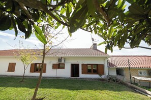 A single-story house with a tiled roof, a small front yard, and a fence.