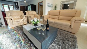 A modern living room with two beige leather sofas, a black coffee table with two wine glasses and a bottle, and a fluffy grey rug. - Private Pool and Hot Tub on the Douro River (São Lourenço do Douro)