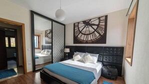 A modern bedroom with a large bed, a clock mural, and a sliding door leading to another room. - Private Pool and Hot Tub on the Douro River (São Lourenço do Douro)