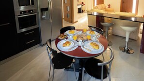 A modern kitchen with a dining table set for breakfast, featuring croissants and orange juice. - Private Pool and Hot Tub on the Douro River (São Lourenço do Douro)