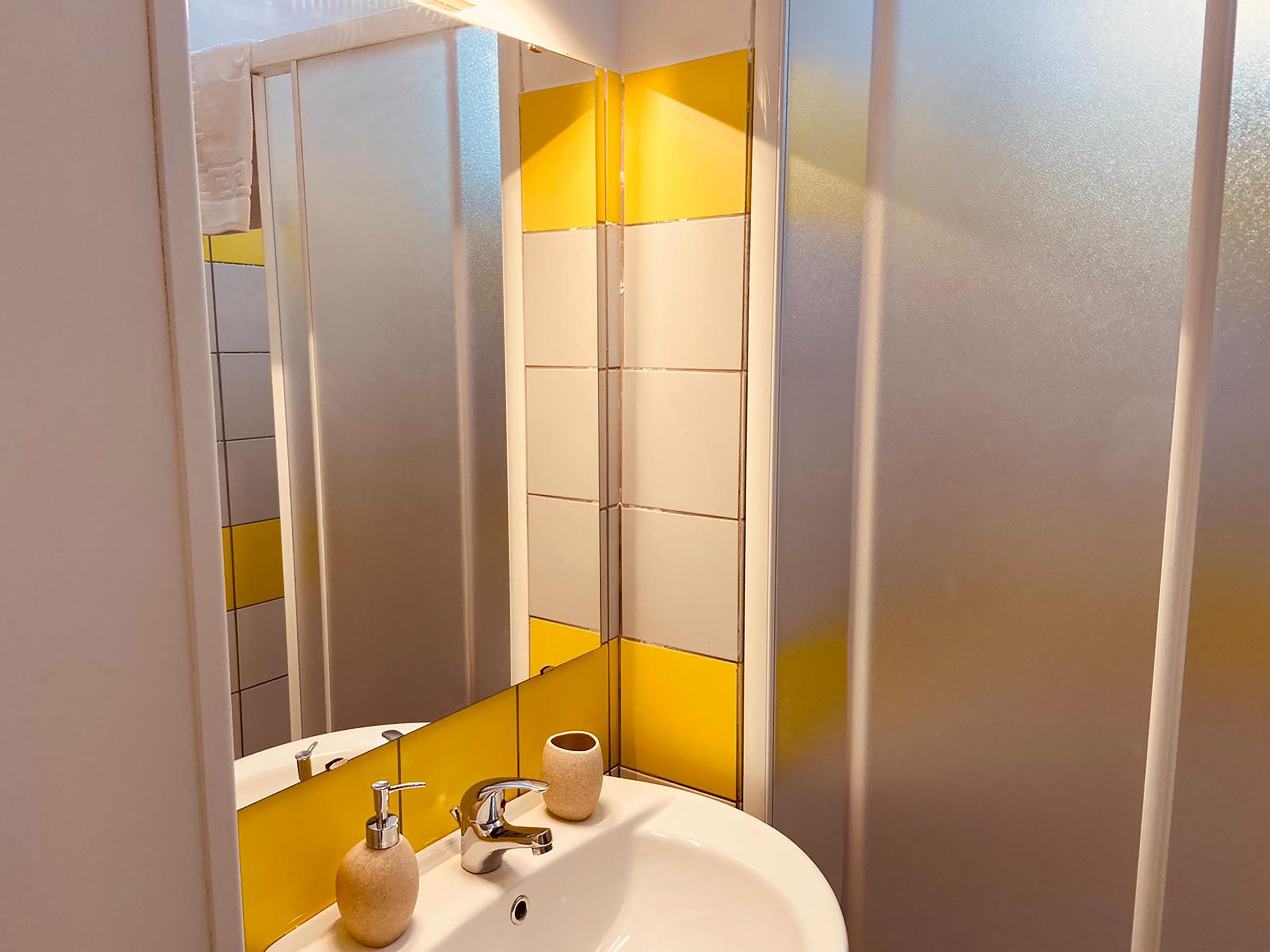 Un baño con un lavamanos blanco, grifo cromado y dos dispensadores de jabón color beige.