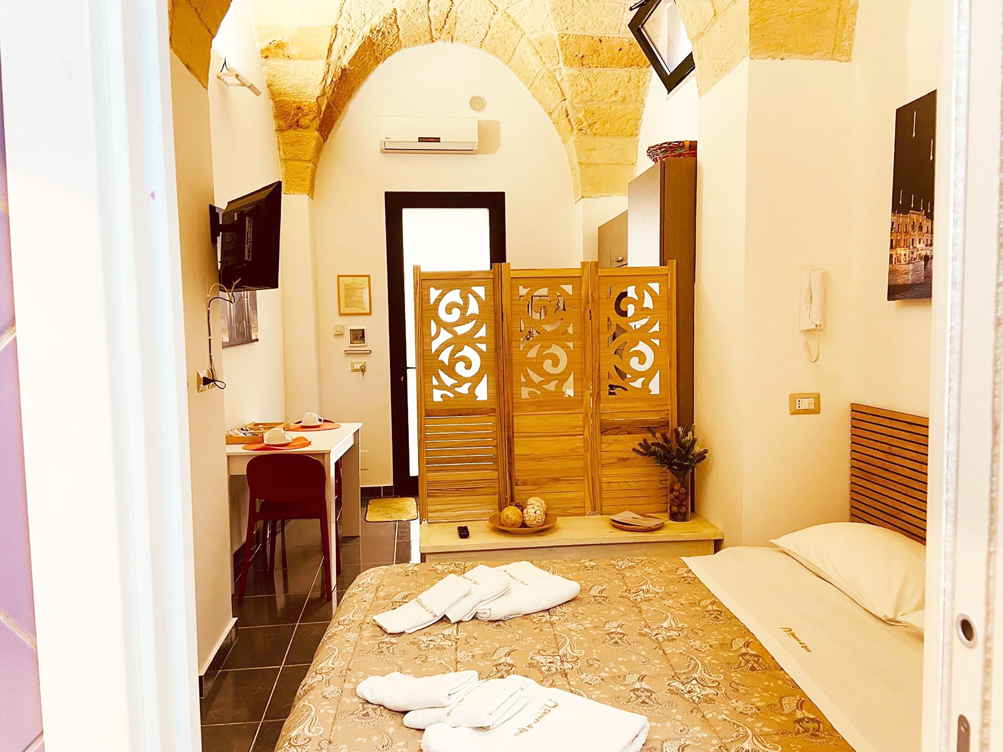 Una habitación de hotel con cama, escritorio, silla, armario y baño.