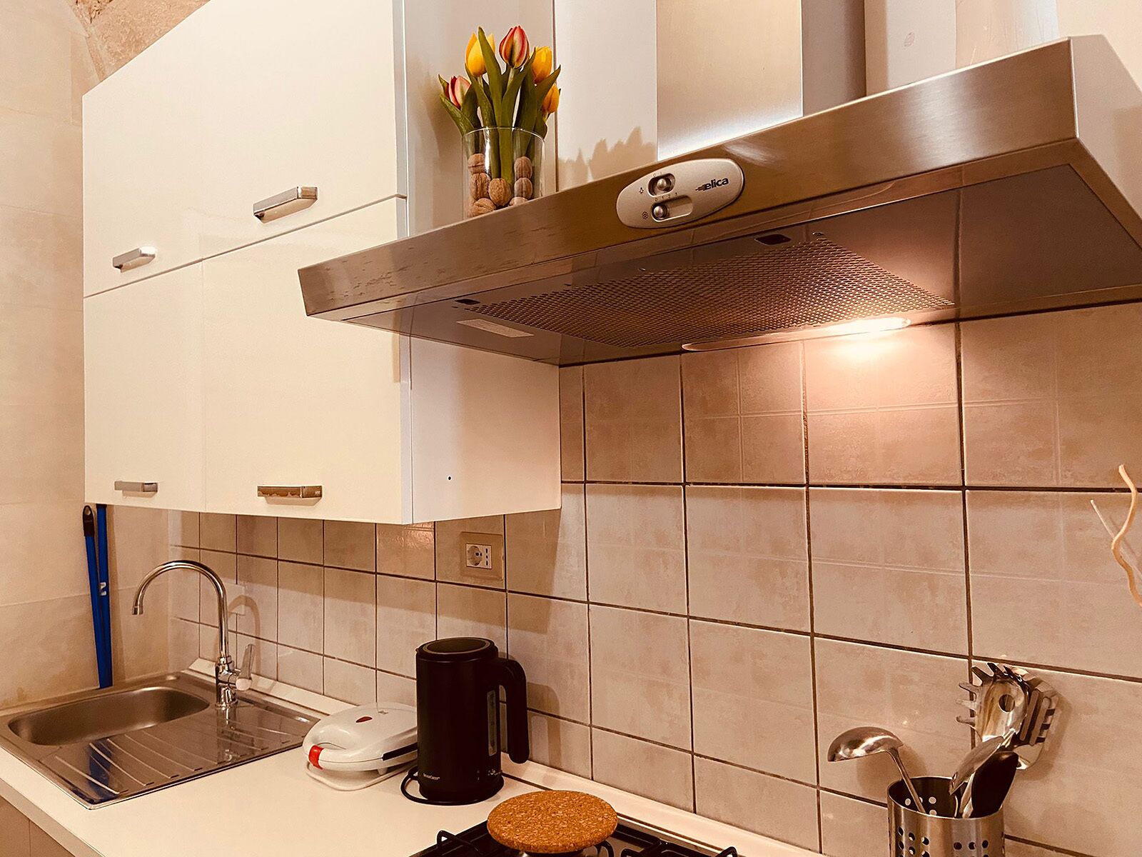 Een moderne keuken met een roestvrijstalen afzuigkap, een koffiezetapparaat en een broodrooster op het aanrecht.
