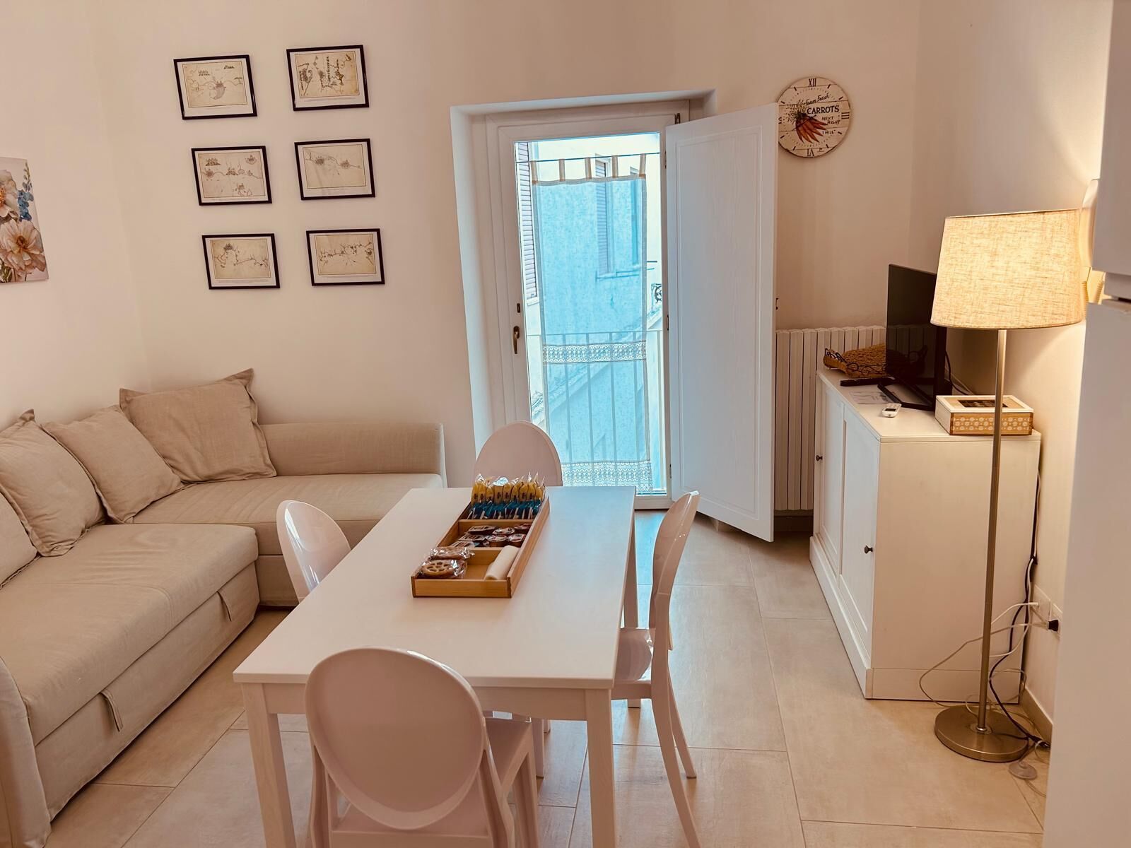 Ein gemütliches Wohnzimmer mit Sofa, Esstisch und Stühlen, einer Lampe und Blick ins Freie.