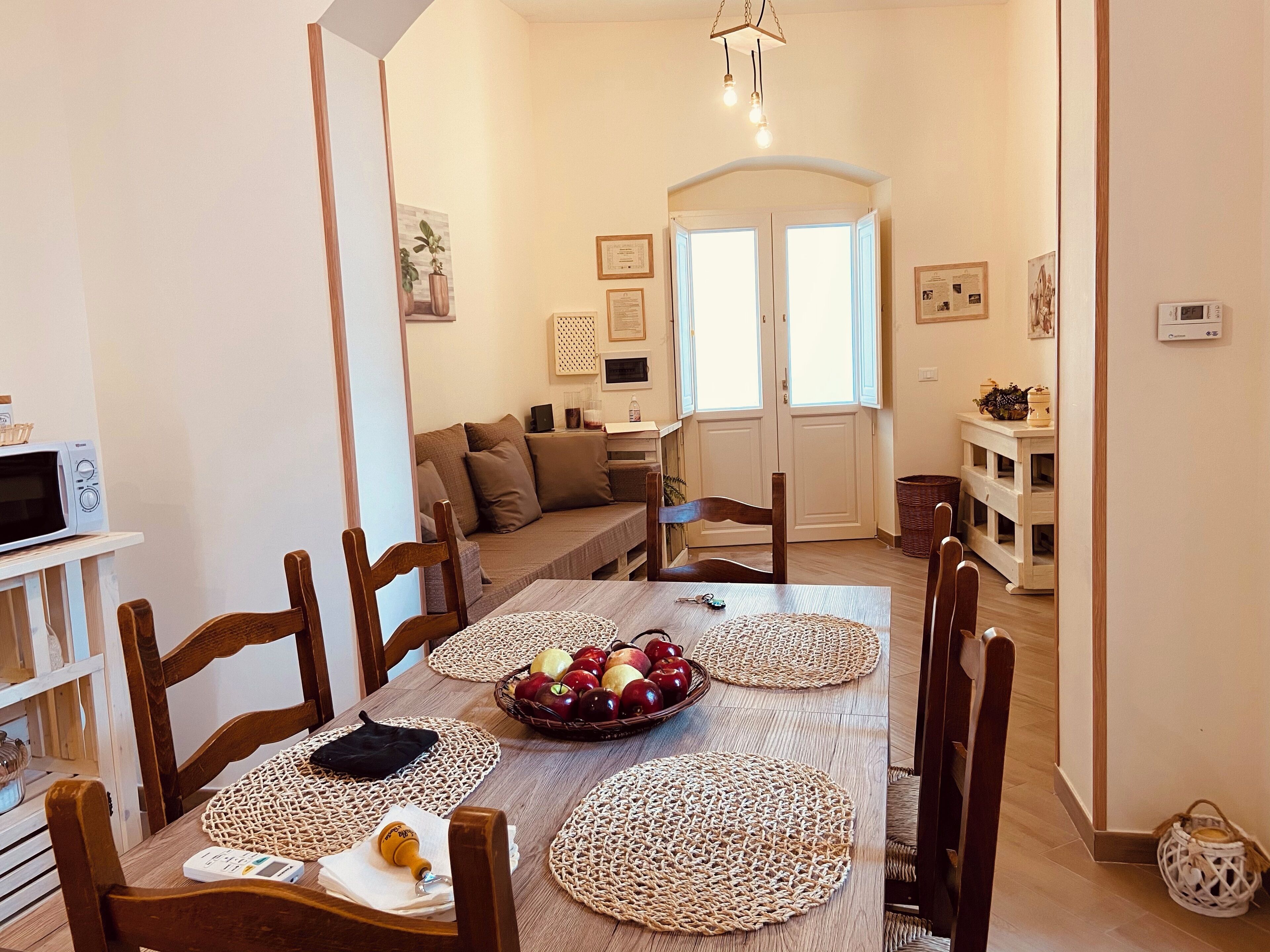 Un comedor con una mesa de madera, individuales tejidos y una cesta de frutas.