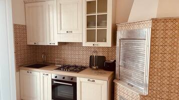 A kitchen with light wooden cabinets, a gas stove, an oven, and a patterned backsplash.